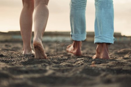 Téléchargez les photos : Close up and legs view for man and woman walking together on the ground in barefoot natural style. Concept of love and life together. Nudism. Couple of people walk. Sky in background. Travel. - en image libre de droit