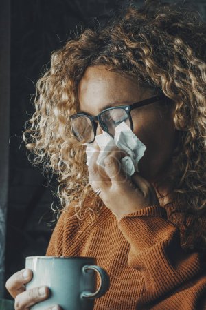 Téléchargez les photos : Woman sneezing nose with fever and influenza virus health disease. Flu and cold for winter temperature at home. People suffering for unhealthy bad condition indoor. Female with paper towels - en image libre de droit