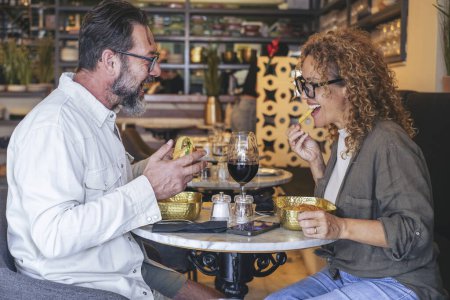 Téléchargez les photos : Couple heureux souriant et parlant dans un restaurant de pub manger des hamburgers et des chips - Couple marié ayant pause déjeuner au café bar - Concept de style de vie avec l'homme et une femme sortant le week-end - en image libre de droit