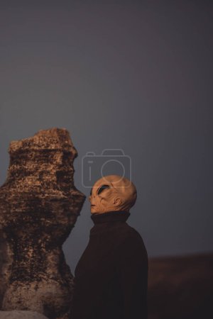 Foto de Mars and other planets life concept with standing ufo and moon landscape around. Outdoor alien mask people side portrait. Concept of diversity and extraterrestrial among us invasion - Imagen libre de derechos