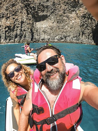 Téléchargez les photos : Joyeux joyeux homme et femme ensemble sur un ciel de jet s'amuser en vacances d'été - Voyage et mode de vie heureux jeunes gens - selfie photo et sourires - océan bleu et le littoral - en image libre de droit