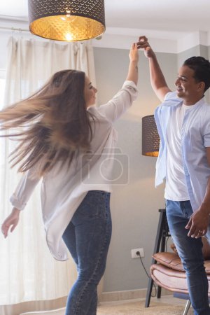 Téléchargez les photos : Pleine longueur de jeune couple insouciant dansant à la maison ensemble - en image libre de droit