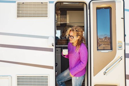 Foto de Mujer bebiendo café sentado en la puerta de una caravana - Imagen libre de derechos