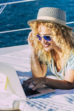 Photo for Cheerful woman work outdoor with laptop computer lay down on a boat enjoying freedom and internet connection - concept of people and smart working modern lifestyle - new job office concept - Royalty Free Image