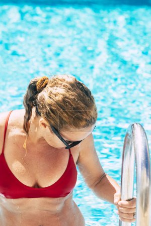 Foto de Hermosa mujer caucásica adulta salir a la piscina con traje de baño de bikini rojo - concepto de vacaciones de vacaciones activas de verano y disfrutar de personas con estilo de vida activo saludable - Imagen libre de derechos