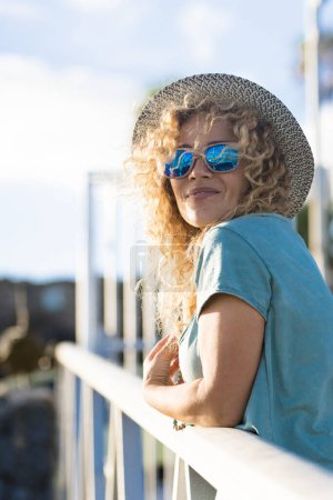 Foto de Mujer bastante adulta sonrisa y disfrutar de la actividad de ocio al aire libre en el día soleado - mujeres de mediana edad personas caucásicas con sombrero de moda - bonito concepto de estilo de vida alegre - Imagen libre de derechos