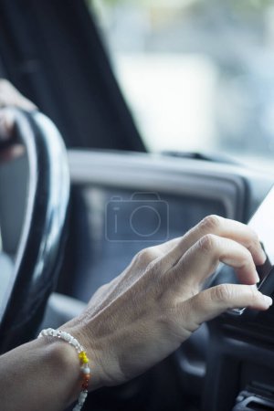 Photo for Close up of woman hand setting the gps online navigator on the phone while drive - people and travel with technology help to find the way - using app application on mobile  inside the car - Royalty Free Image