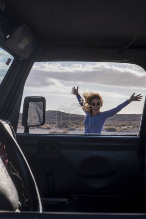 Photo for Happy and free alternative adventure travel tourist woman have fun outside the car with outdoors mountain and wild desert in background - adult female enjoy journey trip vacation with vehicle - Royalty Free Image
