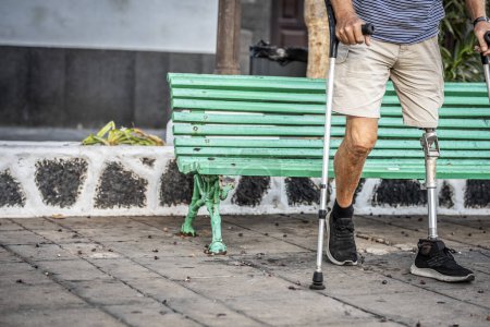 Téléchargez les photos : Membre à part entière de la société, un homme âgé avec une prothèse de titane à la jambe gauche marche en douceur dans un parc urbain - en image libre de droit
