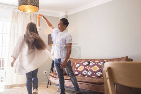 Photo for Full length of carefree young couple dancing at home together - Royalty Free Image