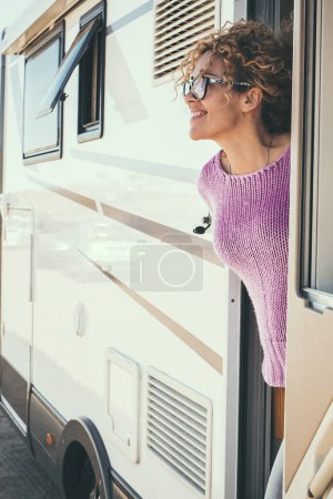 Foto de Mujer mirando y sonriendo fuera de la puerta de una caravana - Imagen libre de derechos