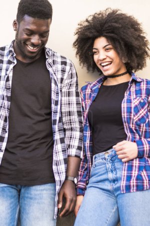 Téléchargez les photos : Heureux noir hipster jeune couple profiter ensemble loisirs en plein air dans la ville avec mur en arrière-plan - en image libre de droit