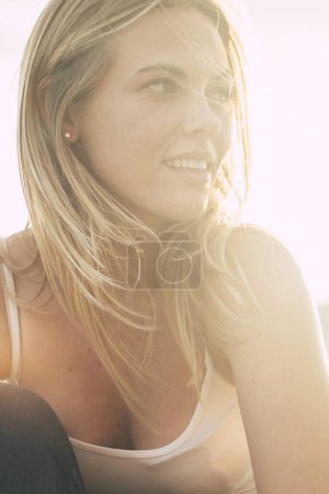 Téléchargez les photos : Portrait de jolie jeune femme gaie sourire et profiter d'activités de loisirs en plein air assis sur la plage avec un soleil éclatant en arrière-plan - personnes heureuses et mode de vie jeune - blonde fille aux cheveux longs - en image libre de droit