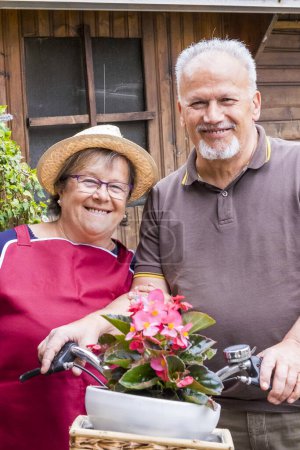 Photo for Outdoor happy portrait of old senior man and woman together smiling - garden home activity for retired couple - two cheerful elderly lifestyle in outdoor leisure activity - Royalty Free Image
