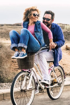 Photo for Joyful love friendship concept - happy adult caucasian, couple having fun with bicycle in outdoor leisure activity. concept of active playful people with bike during vacation - everyday joy lifestyle without age limitation - Royalty Free Image