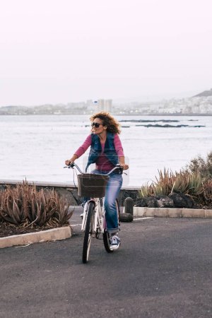 Téléchargez les photos : Femme faire du vélo en plein air avec vue sur la côte océan - mode de vie sain transport environnement vert et monde respecter les gens - touriste profiter des vacances à cheval sur la route - en image libre de droit