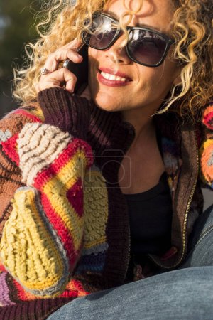 Foto de Retrato de alegre feliz hermosa mujer haciendo llamada telefónica en el día soleado ocio al aire libre actividad de viaje solo - concepto de alegre bonita mujer en el estilo de vida de primavera de verano sonriendo - Imagen libre de derechos