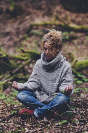 Foto de La mujer se sienta al aire libre en medio de la naturaleza y los bosques meditan en posición de loto yoga con los ojos cerrados Mindfulness y la naturaleza conectan a las personas. Mujer dama han relajado y cuidar su estilo de vida equilibrio interior - Imagen libre de derechos