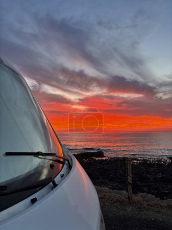 Photo for Amazing sunset viewed from outiside a camper van parking on the coast. Freedom and journey alternative vanlife lifestyle. Renting motorhome for summer vacation sunrise on the ocean - Royalty Free Image
