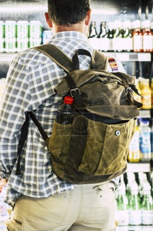 Photo for Back view of man buying drinks and food from automatic machine before travel. Concept of modern traveler lifestyle. People with backpack in front of a 24h opened store with beverages and snacks - Royalty Free Image