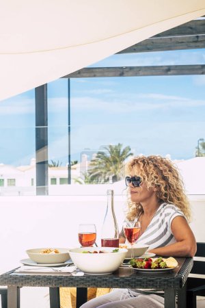 Photo for Adult pretty woman waiting her husband to have lunch together outdoor home in the terrace. Summer holiday renting property vacation concept lifestyle. People and brunch leisure time - Royalty Free Image