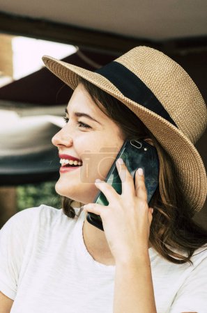 Beautiful young woman speak at the phone calling freinds outdoor - portrait side view of pretty girls smiling and enjoying communication activity - modern trendy female with cellular
