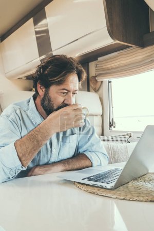 Photo for Man use computer inside camper van during travel vacation or van life lifestyle. Modern man and woman work together on laptop in alternative office motor home. Digital nomad and smart free working - Royalty Free Image
