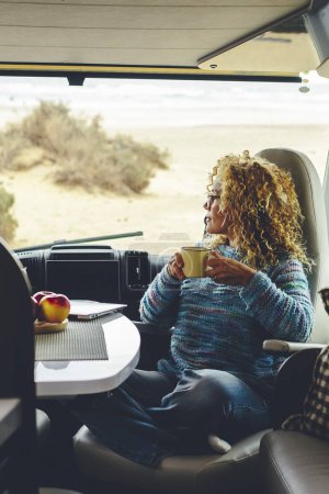 Téléchargez les photos : Femme camping-car tout en voyageant avec café en van - en image libre de droit