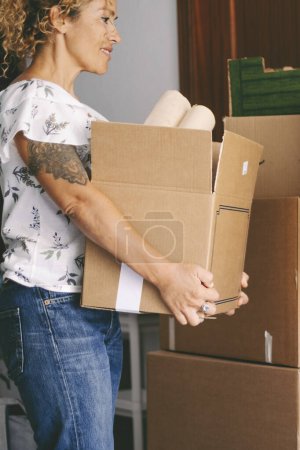 Photo for Modern female working at home with cardboard boxes for moving and renovating indoor leisure activity. Young female busy with boxes and packages. Mortgage and loan with people. Changing life concept lady - Royalty Free Image