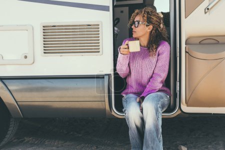 Foto de Mujer bebiendo café sentado en la puerta de una caravana - Imagen libre de derechos