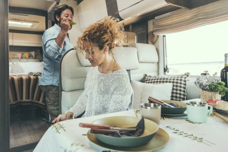 Téléchargez les photos : Couple en camping-car relaxant préparer le déjeuner et profiter du temps libre - en image libre de droit