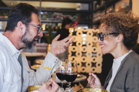 Téléchargez les photos : Couple heureux souriant et parlant au restaurant - Couple marié en pause déjeuner au café-bar - Concept de style de vie avec l'homme et une femme qui sort le week-end - en image libre de droit