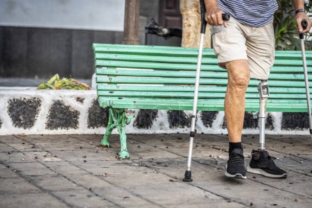Téléchargez les photos : Un membre à part entière de la société un homme âgé avec une prothèse de titane jambe gauche marche en douceur dans un parc de la ville - en image libre de droit