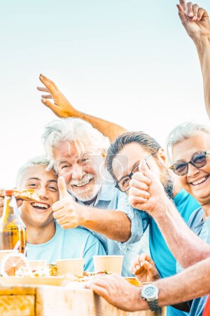 Photo for Multigenerational family having lunch on a terrace on a beautiful sunny day. 18 year old boy laughs with his grandparents celebrating. Lifestyle and family concept - Royalty Free Image