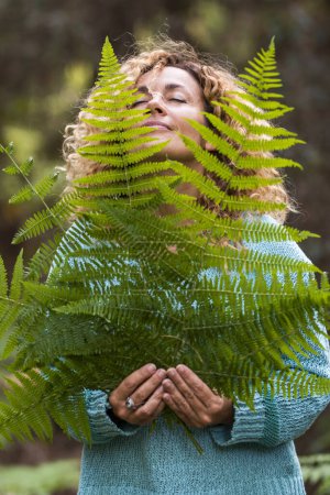 Foto de Día de la Tierra y el amor por el concepto de la naturaleza con la hermosa mujer con los ojos cerrados sentir las hojas grandes y disfrutar de la actividad de ocio natural al aire libre - salvar el bosque y no deforestación estilo de vida - Imagen libre de derechos