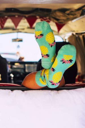 Photo for Travel lifestyle with minivan and vanlife style - unrecognizable girl inside a retro camper - feet with socks visible from a lay down unrecognizable people - Royalty Free Image