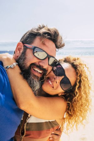 Téléchargez les photos : Couple heureux et en bonne santé de personnes profitant de leur vie et leurs vacances à l'extérieur à la plage ensemble prendre un selfie avec la mer ou l'océan en arrière-plan deux personnes heureuses prenant une photo sur le sable - en image libre de droit