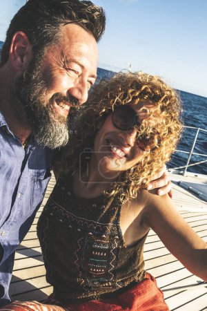 Photo for Happy adult caucasian couple together on a sailboat enjoy vacation or excursion - people in outdoor leisure activity on boat with blue ocean and sky around. happiness and love man and woman - Royalty Free Image
