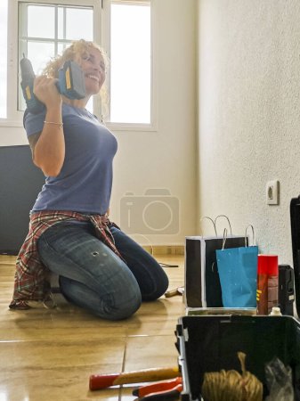 Téléchargez les photos : Femme heureuse et fatiguée se reposer sur le sol après le travail à domicile pendant une hypothèque - nouvelle maison et concept de vie - les gens aiment le changement et bricolage emplois - concept d'indépendance pour les femmes - en image libre de droit