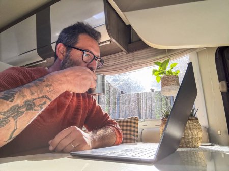 Photo for Digital nomad working inside a camper van travel lifestyle vehicle vanlife using laptop computer and roaming internet connection. People and telecommuting remote worker. Life in motorhome. Modern - Royalty Free Image