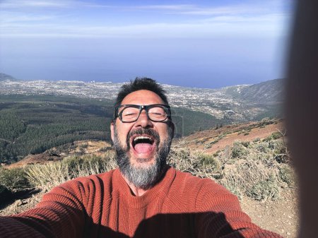 Téléchargez les photos : Homme adulte prenant selfie photo dans le fond de la vue panoramique de montagne. - en image libre de droit