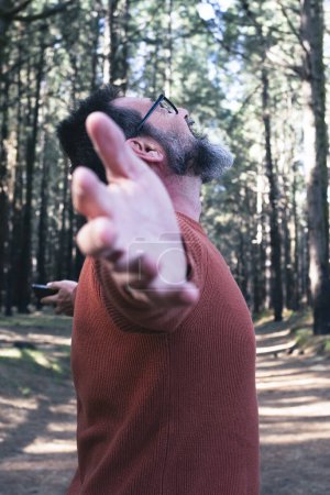 Foto de Hombre libre extendiendo los brazos de apertura en la actividad de ocio al aire libre con árboles forestales parque bosques en el fondo. Gente y naturaleza sintiendo. Respirando afuera. Bienestar y estilo de vida. Viajes escénicos - Imagen libre de derechos