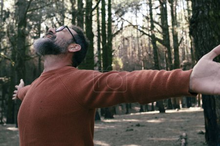 Téléchargez les photos : Homme libre écartant les bras ouvrant dans l'activité de loisirs de plein air avec des arbres forestiers parc bois en arrière-plan. Les gens et la nature se sentent. Respirez dehors. Bien-être et mode de vie. Voyage pittoresque - en image libre de droit
