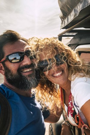 Téléchargez les photos : Joyeux adulte heureux couple caucasien profiter Voyage en voiture et prendre selfie photo souriant avec amitié et relation concept de mode de vie sain et libre - en image libre de droit