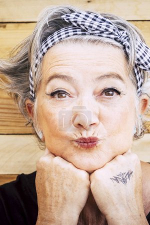Téléchargez les photos : Portrait de femme heureuse âgée caucasienne joyeuse avec fond de bois - sourire et plaisir alternatif et jeune vieille femme - peau tatouée pour le concept de diversité et l'âge - en image libre de droit