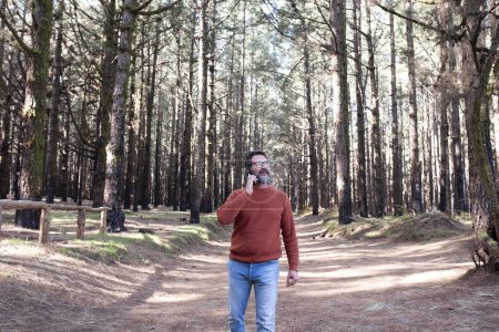 Téléchargez les photos : Homme avec téléphone portable en forêt profiter des vacances - en image libre de droit