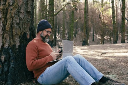 Photo for Man using technology connection in nature park forest woods. Remote worker small travel business lifestyle people. Working in the nature alternative office. Small business. Travelers job life - Royalty Free Image