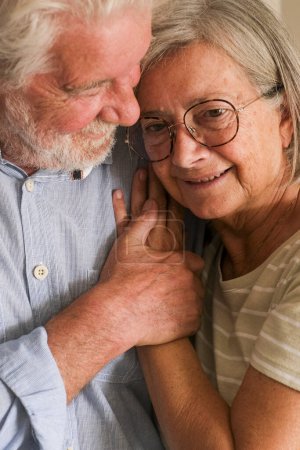 Foto de Amor a la mayor edad entre un hombre maduro y una anciana en casa, abrazándose y protegiéndose mutuamente con expresión romántica. Retrato de personas jubiladas cuidando y disfrutando juntos de un estilo de vida anciano - Imagen libre de derechos