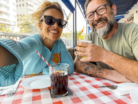 Téléchargez les photos : Couple souriant profiter du temps au restaurant boire et parler en plein air dehor s'amuser ensemble. Consommation, alimentation, mode de vie concept - en image libre de droit