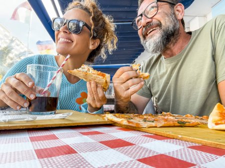 Photo for Smiling couple enjoy lunch at pizzeria. Beautiful smiling couple enjoying pizza, having fun together. Consumerism, food, lifestyle concept - Royalty Free Image